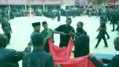 Hoisting the black flag of Imam Hussein above the dome of a Husainiyyah in Nigeria