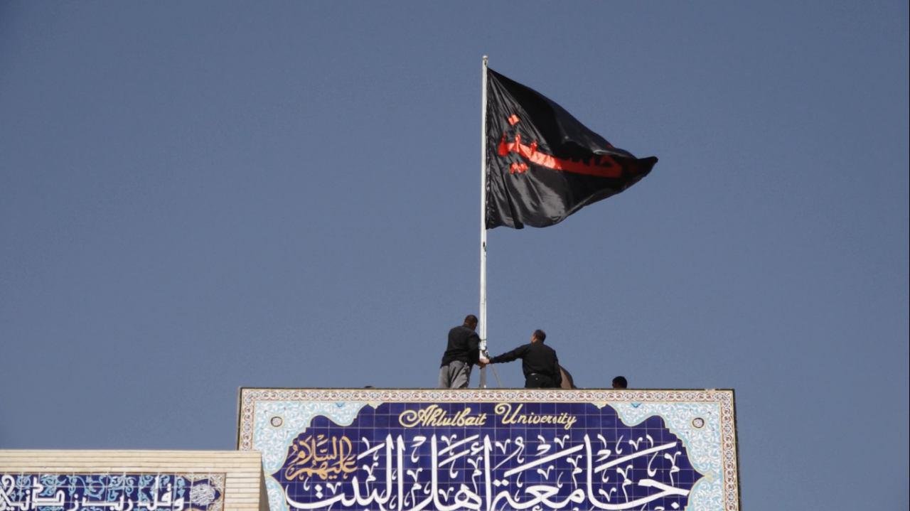 تصویر برافراشتن پرچم امام حسین علیه السلام در  «دانشگاه اهل بیت علیهم السلام» در کربلا